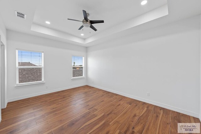 unfurnished room with hardwood / wood-style flooring, ceiling fan, and a raised ceiling