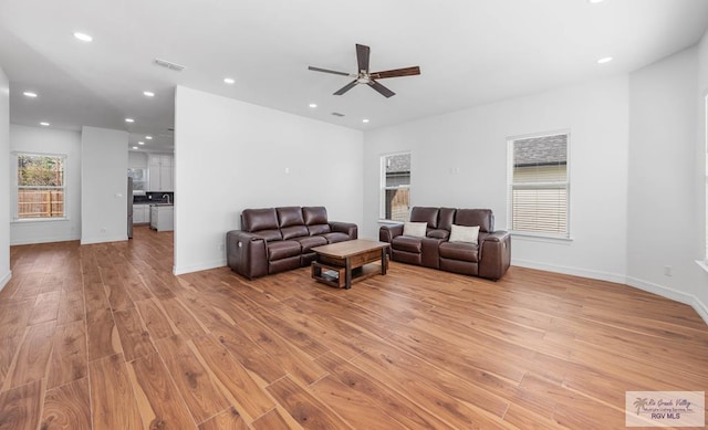 living room with light wood-type flooring and ceiling fan