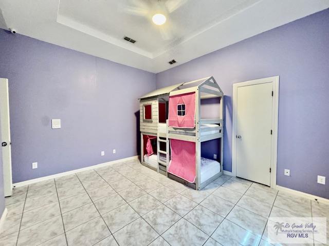 unfurnished bedroom with tile patterned floors, a raised ceiling, and ceiling fan