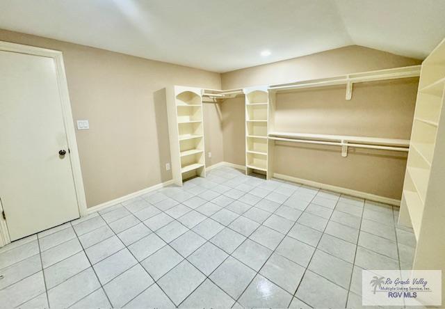 spacious closet with light tile patterned flooring and vaulted ceiling