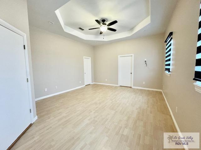 spare room featuring ceiling fan, light hardwood / wood-style floors, and a raised ceiling