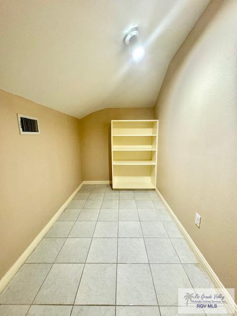 unfurnished room featuring tile patterned flooring and vaulted ceiling