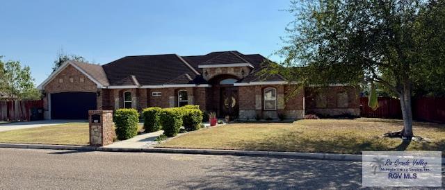 2909 Mi Cielo Dr, Weslaco, TX 78599 - view of front of house featuring an attached garage, stone siding, concrete driveway, and a front yard