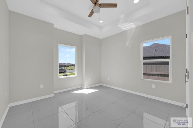 4698 Kalinga Ln, Brownsville, TX 78521 - empty room with marble look tiles, baseboards, a ceiling fan, a tray ceiling, and recessed lighting