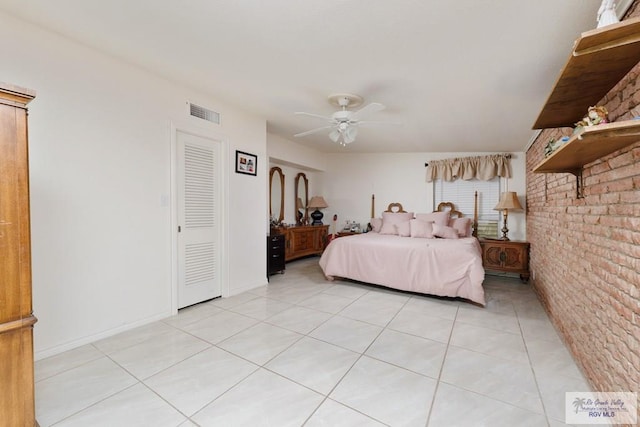 tiled bedroom featuring ceiling fan, a closet, and brick wall