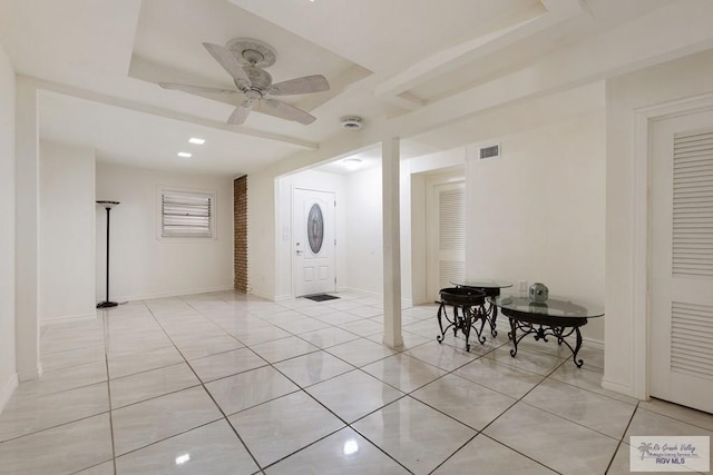 entrance foyer with a raised ceiling, ceiling fan, and light tile patterned floors