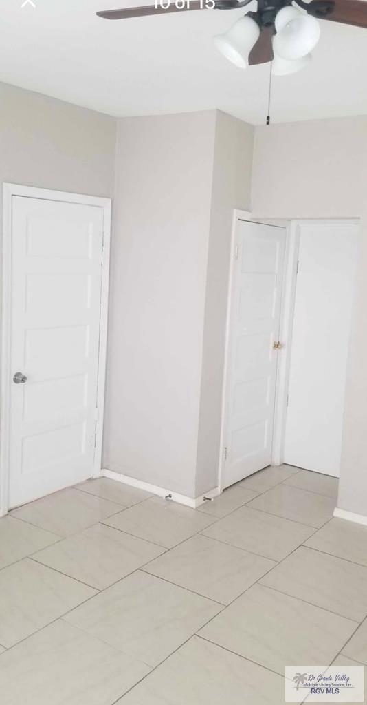 tiled empty room featuring ceiling fan