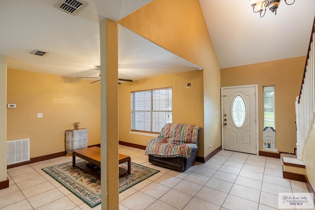 tiled entryway featuring ceiling fan with notable chandelier and vaulted ceiling