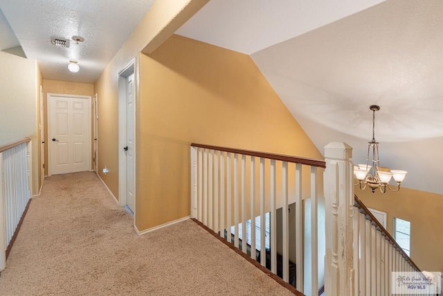 corridor featuring light carpet, lofted ceiling, and a notable chandelier