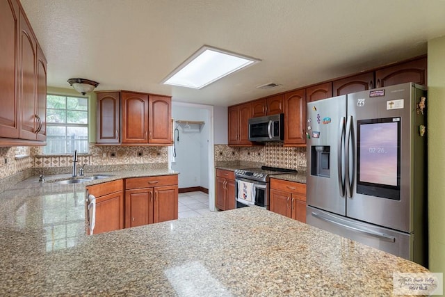 kitchen featuring light stone counters, sink, light tile patterned floors, and stainless steel appliances