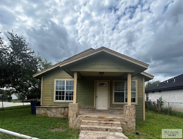 bungalow-style house featuring covered porch and a front yard