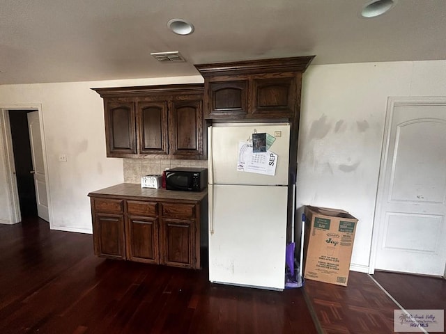 kitchen featuring tasteful backsplash, dark brown cabinets, dark hardwood / wood-style floors, and white refrigerator