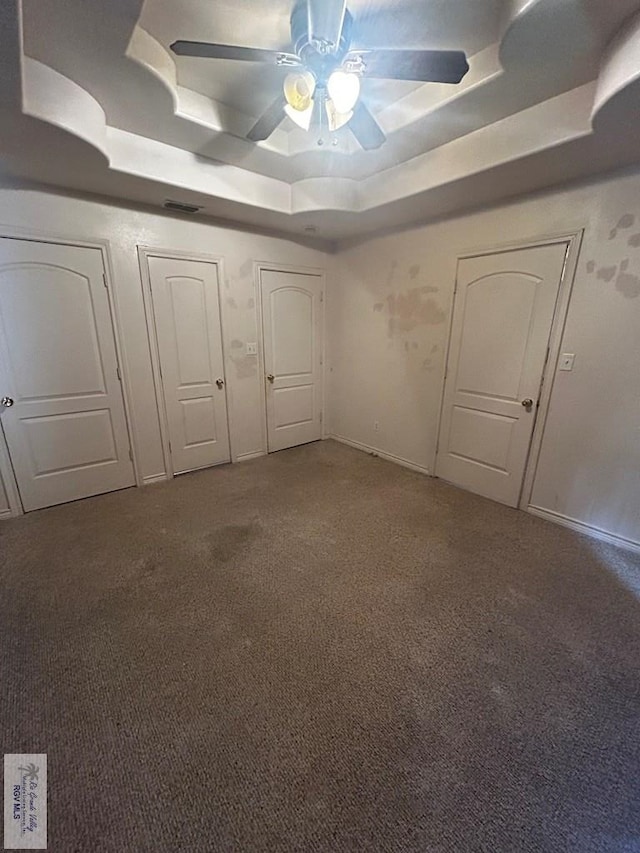 unfurnished bedroom with carpet, ceiling fan, and a tray ceiling