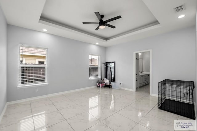 unfurnished room with visible vents, marble finish floor, baseboards, a tray ceiling, and a ceiling fan