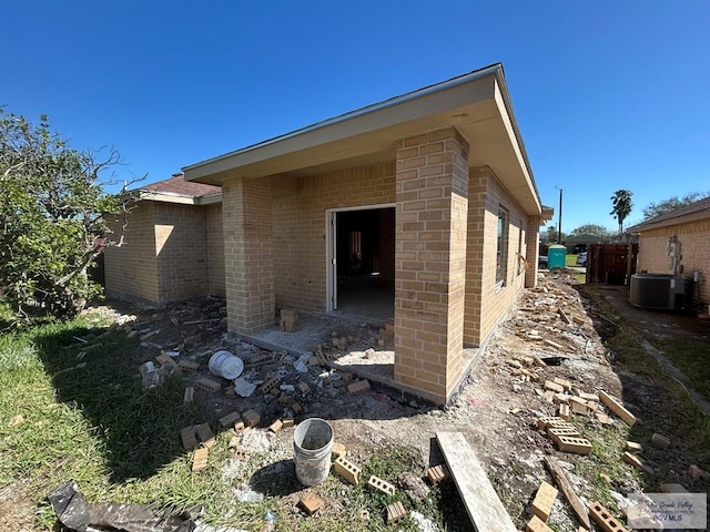 view of side of home with cooling unit and brick siding