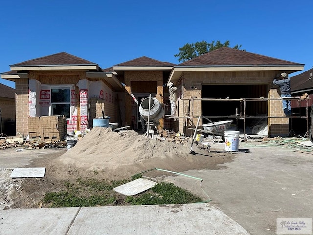 view of front of house with brick siding and roof with shingles