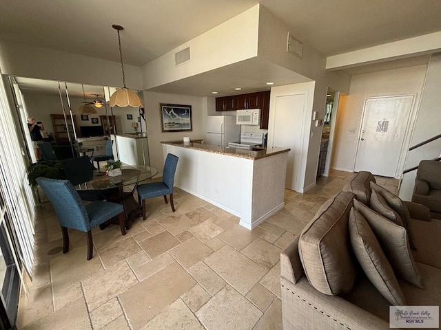 kitchen with ceiling fan, stone counters, hanging light fixtures, kitchen peninsula, and white appliances