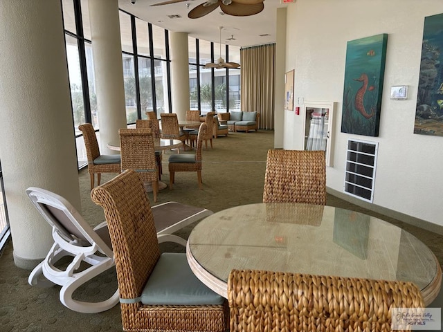 carpeted dining area featuring a wall of windows and ceiling fan