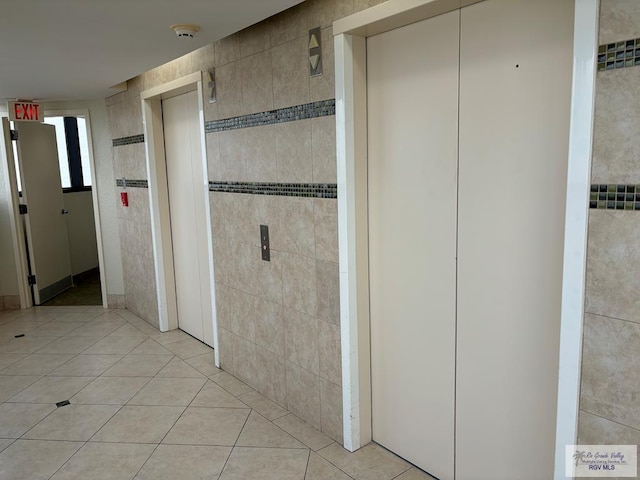 bathroom with tile patterned flooring, elevator, and tile walls