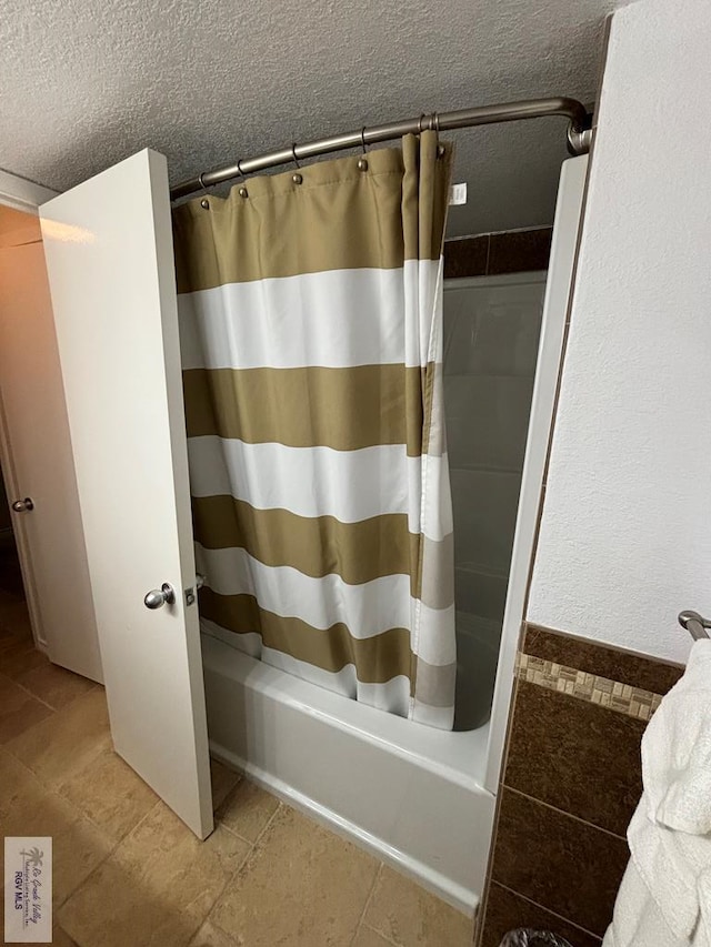 bathroom with tile patterned flooring, shower / bath combination with curtain, and a textured ceiling