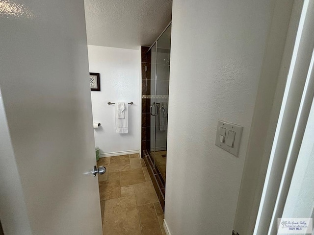 bathroom with a shower with door, a textured ceiling, and toilet