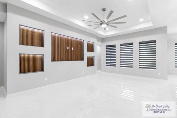 unfurnished room with marble finish floor, ceiling fan, a raised ceiling, and recessed lighting