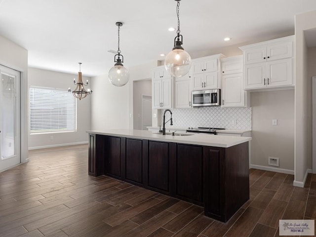 23756 Richmond Cir, Harlingen, TX 78552 - kitchen featuring stainless steel microwave, white cabinetry, tasteful backsplash, dark wood-type flooring, and light countertops