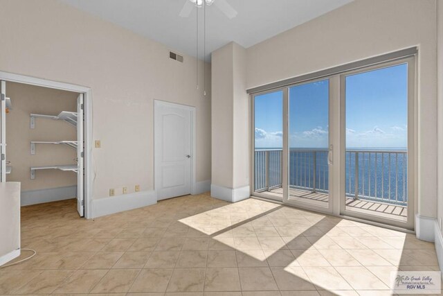 201 W Capricorn Dr, South Padre Island, TX 78597 - unfurnished bedroom featuring access to exterior, light tile patterned floors, baseboards, ceiling fan, and a walk in closet