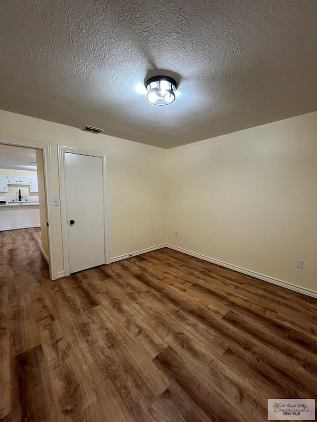 unfurnished room featuring hardwood / wood-style flooring and a textured ceiling