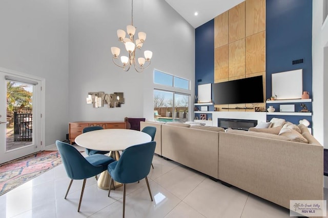 tiled dining area with a wealth of natural light, a chandelier, and a high ceiling