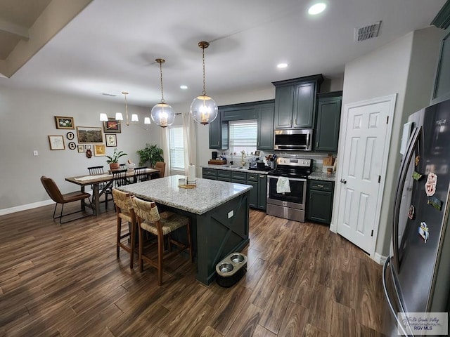 kitchen with a breakfast bar area, stainless steel appliances, a center island, dark hardwood / wood-style flooring, and decorative light fixtures