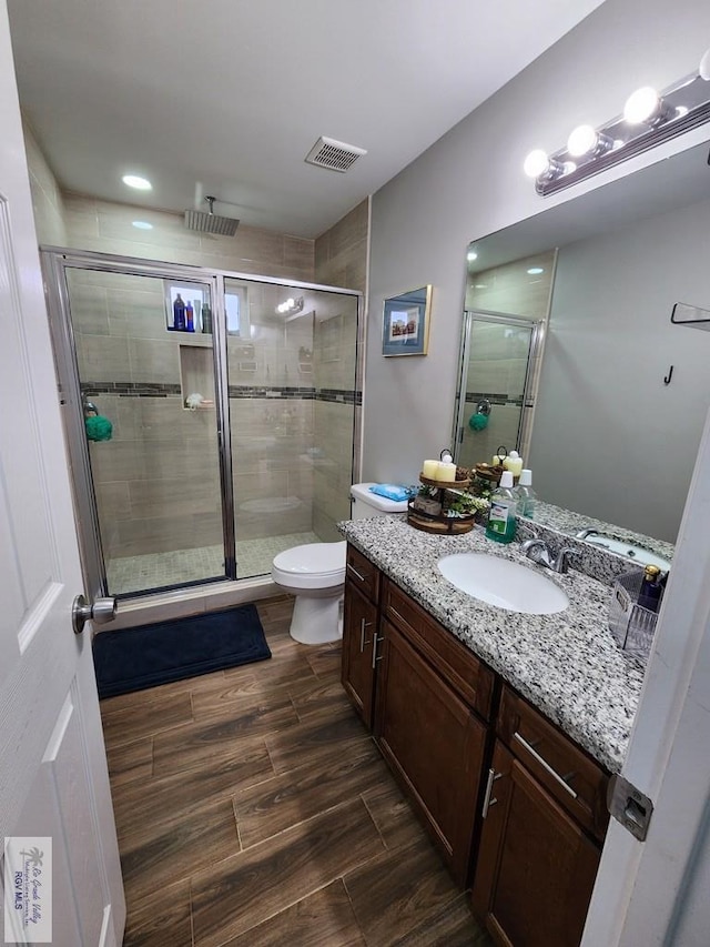 bathroom featuring a shower with door, wood-type flooring, vanity, and toilet