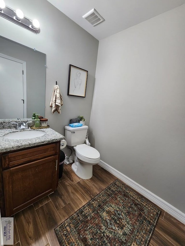 bathroom featuring vanity, hardwood / wood-style flooring, and toilet