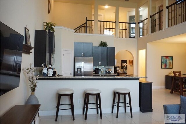 kitchen featuring kitchen peninsula, a breakfast bar, a towering ceiling, and appliances with stainless steel finishes