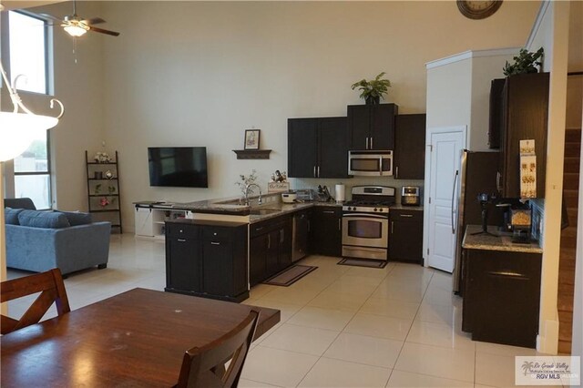 kitchen featuring ceiling fan, sink, a high ceiling, light tile patterned floors, and appliances with stainless steel finishes