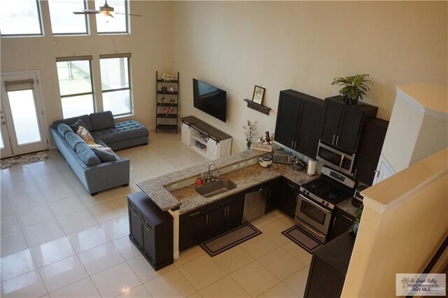 living room with ceiling fan, light tile patterned floors, sink, and a high ceiling