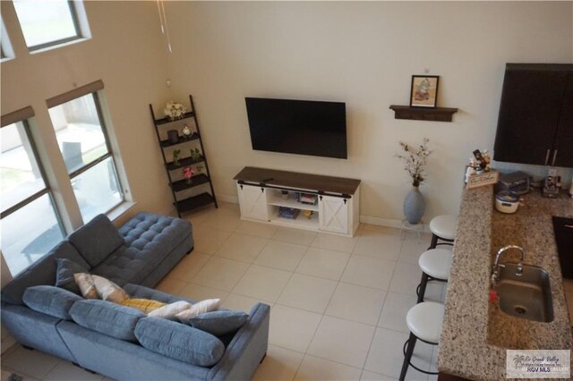 living room with a wealth of natural light, sink, and light tile patterned flooring