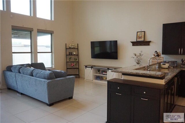 living room with a high ceiling, light tile patterned floors, and sink