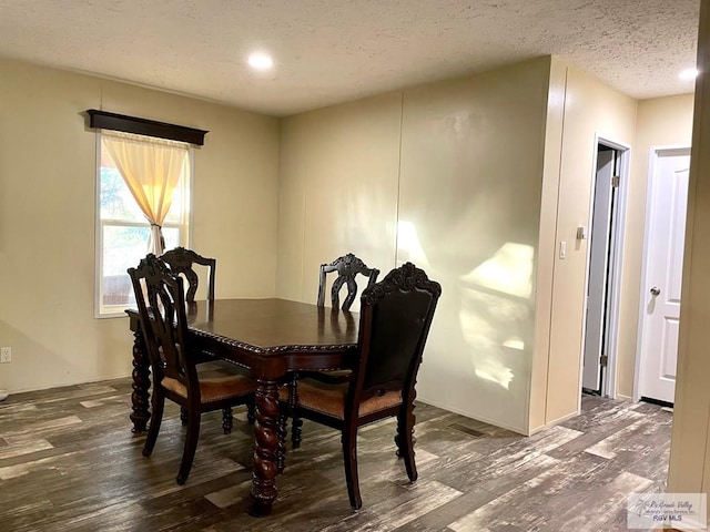 dining room with dark wood-type flooring and a textured ceiling