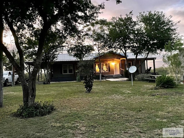 back house at dusk featuring a lawn