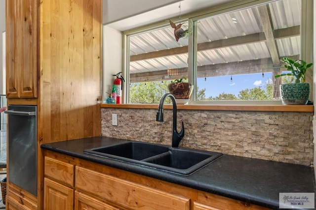 25096 Rabb Rd, La Feria, TX 78559 - kitchen featuring decorative backsplash, dark countertops, brown cabinets, and plenty of natural light
