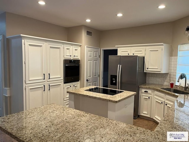 901 Morelos Ave, Rancho Viejo, TX 78575 - kitchen featuring black appliances, light stone countertops, a center island, white cabinetry, and recessed lighting