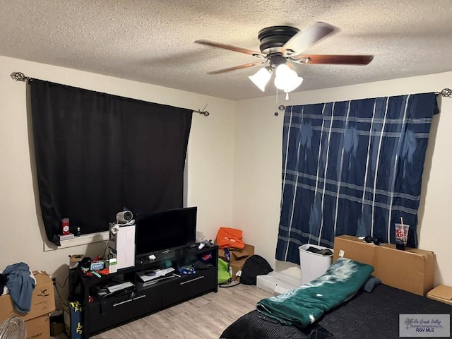 bedroom with a ceiling fan, wood finished floors, and a textured ceiling