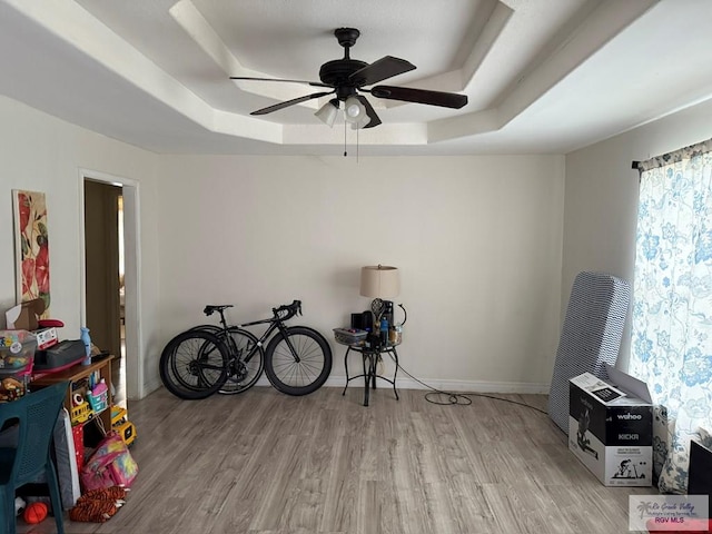 misc room with a raised ceiling, light wood-style floors, and baseboards