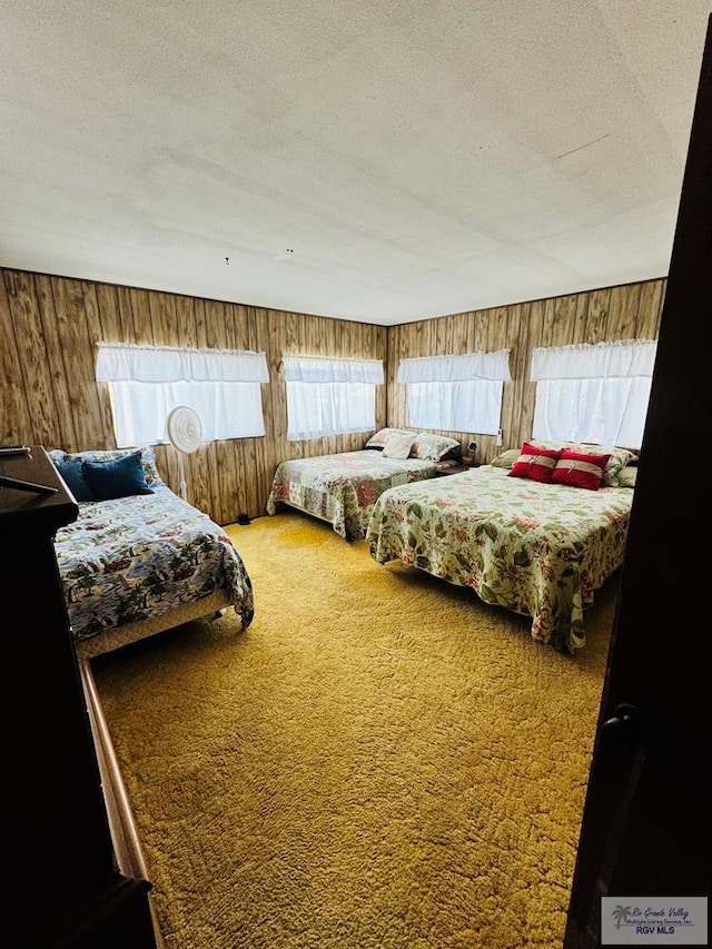 bedroom featuring carpet, a textured ceiling, and wooden walls