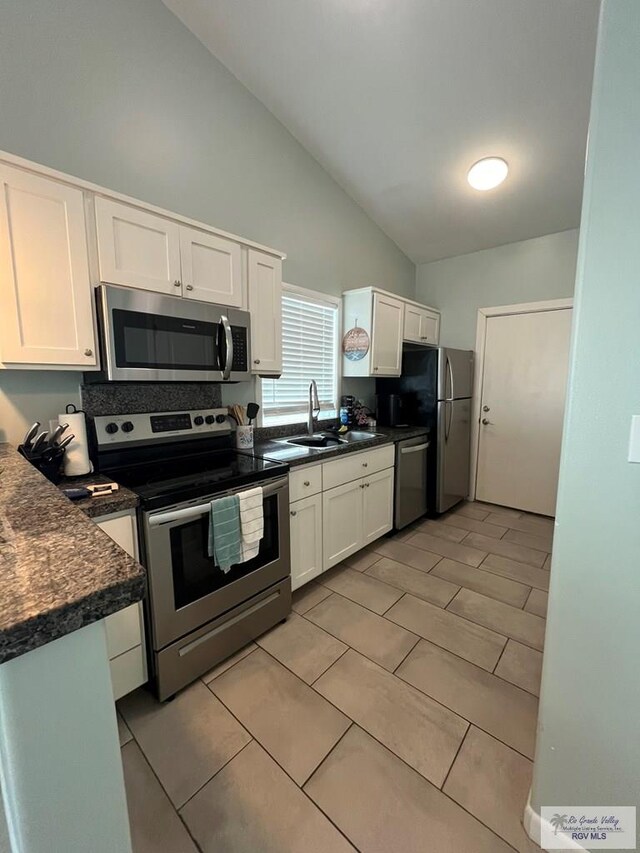 kitchen featuring high vaulted ceiling, sink, light tile patterned floors, appliances with stainless steel finishes, and white cabinetry