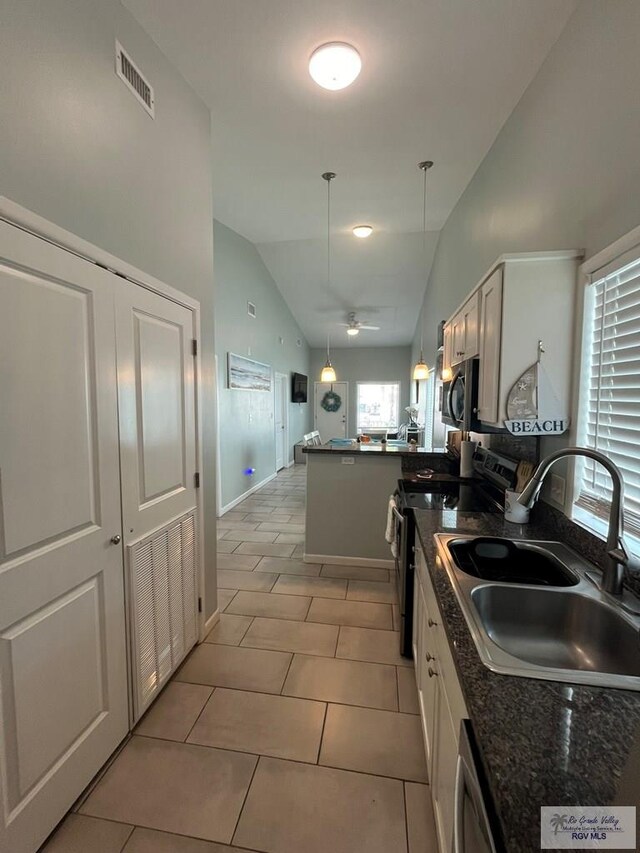 kitchen featuring lofted ceiling, white cabinets, sink, decorative light fixtures, and stainless steel appliances