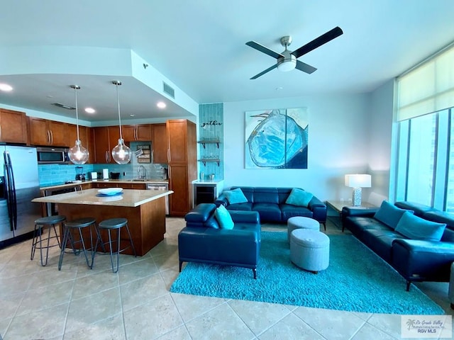 living room with sink, light tile patterned floors, and ceiling fan