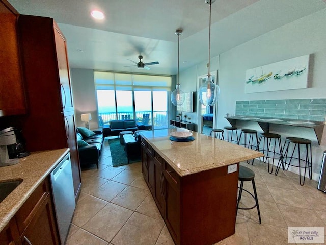 kitchen featuring a breakfast bar, light stone counters, a center island, hanging light fixtures, and stainless steel dishwasher