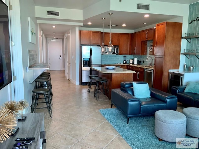 kitchen with appliances with stainless steel finishes, tasteful backsplash, a breakfast bar area, hanging light fixtures, and a center island